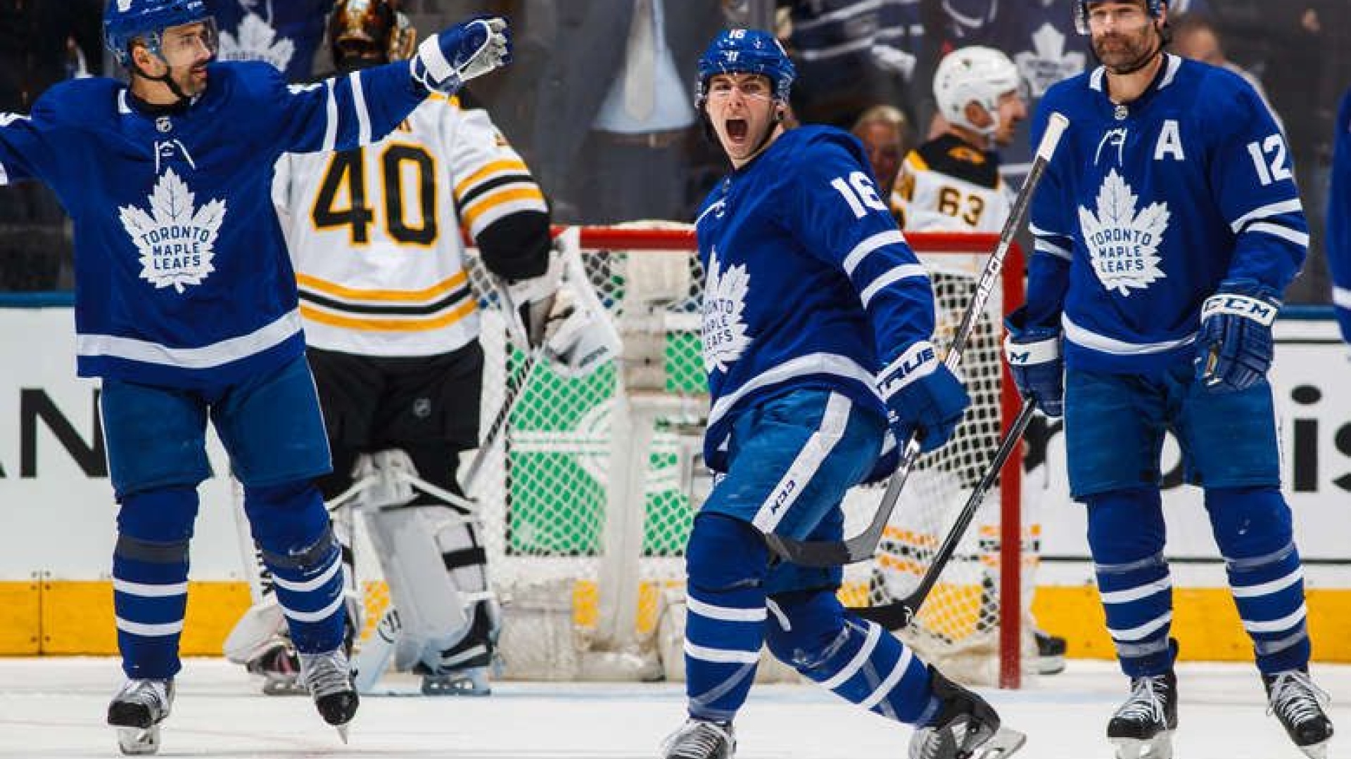 Marner célébrant un but aux côtés de Tomas Plekanec et de Patrick Marleau